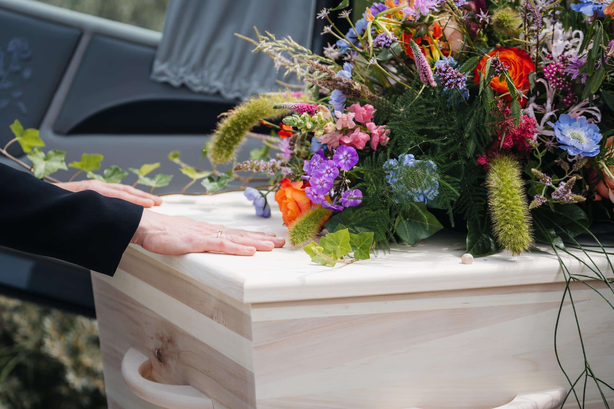 hand op kist begrafenis of crematie katwijk